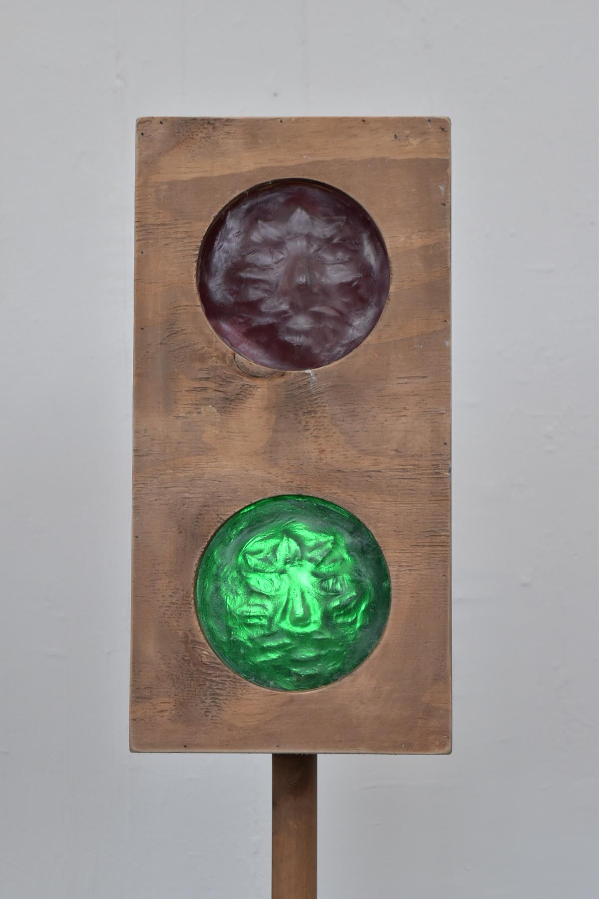 a wooden traffic light, with the green light illuminating a glass face.