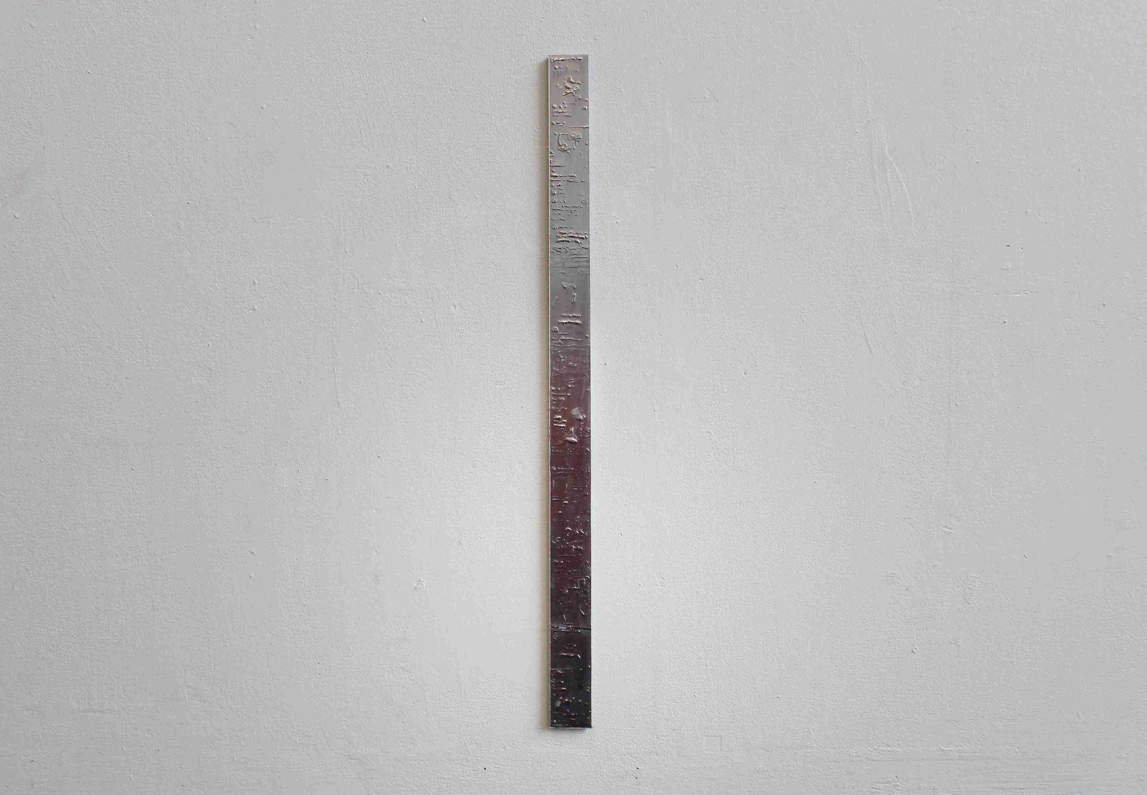 Thin, long, metal looking painting on white wall.