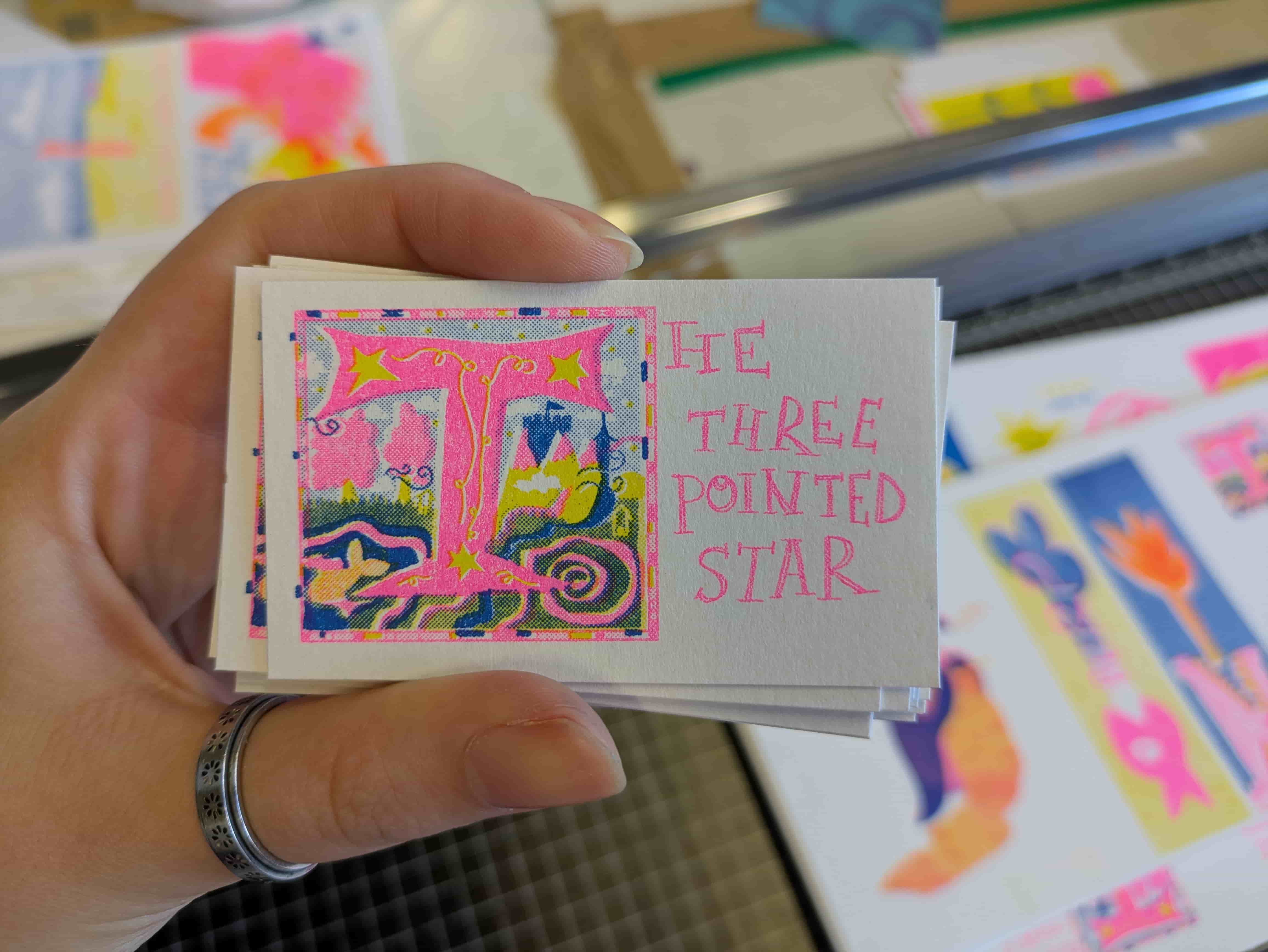 A risograph printed business card with The Three Pointed Star text on 