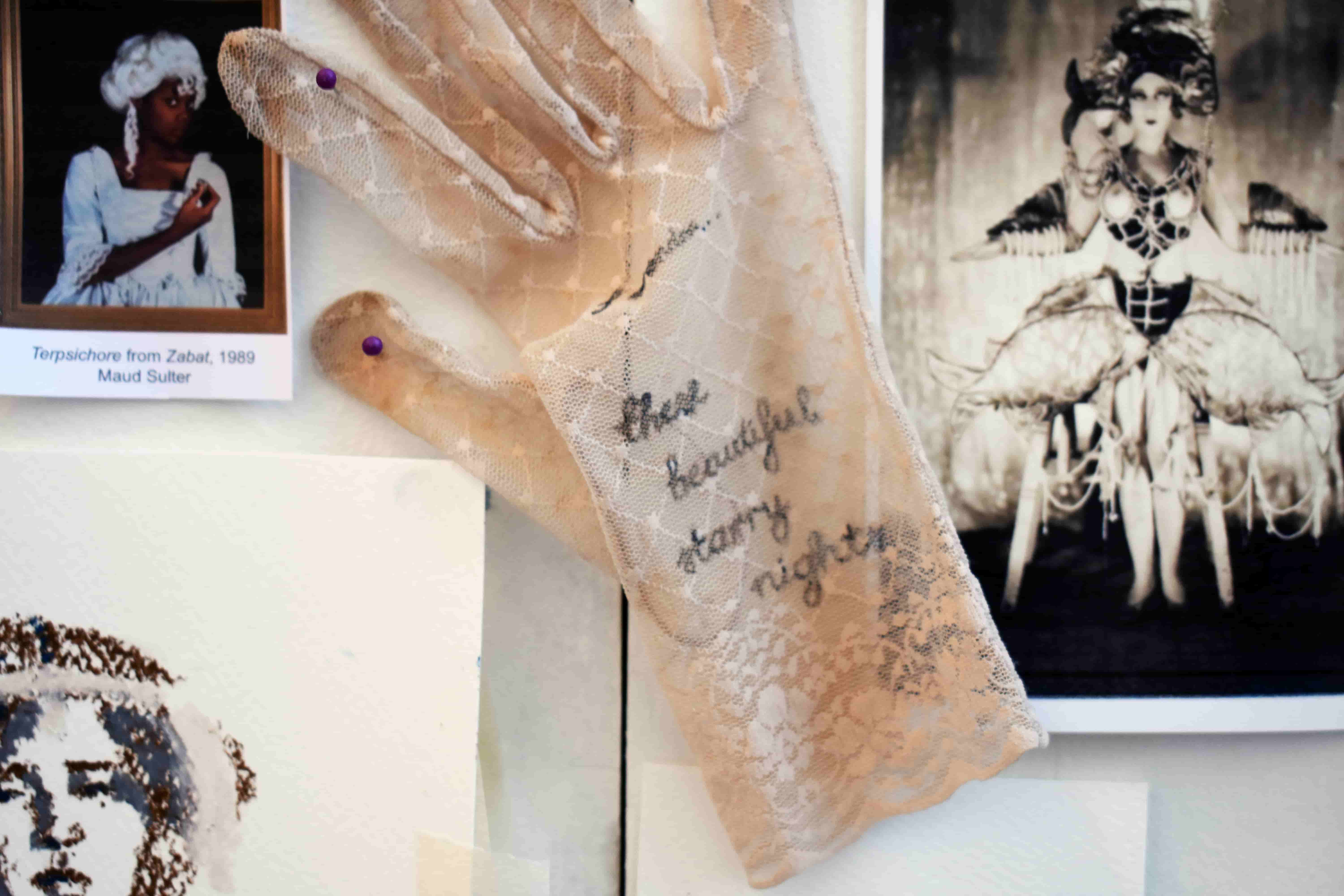 detail of studio wall, showing a lace glove with ink writing that reads I wonder...these beautiful starry nights