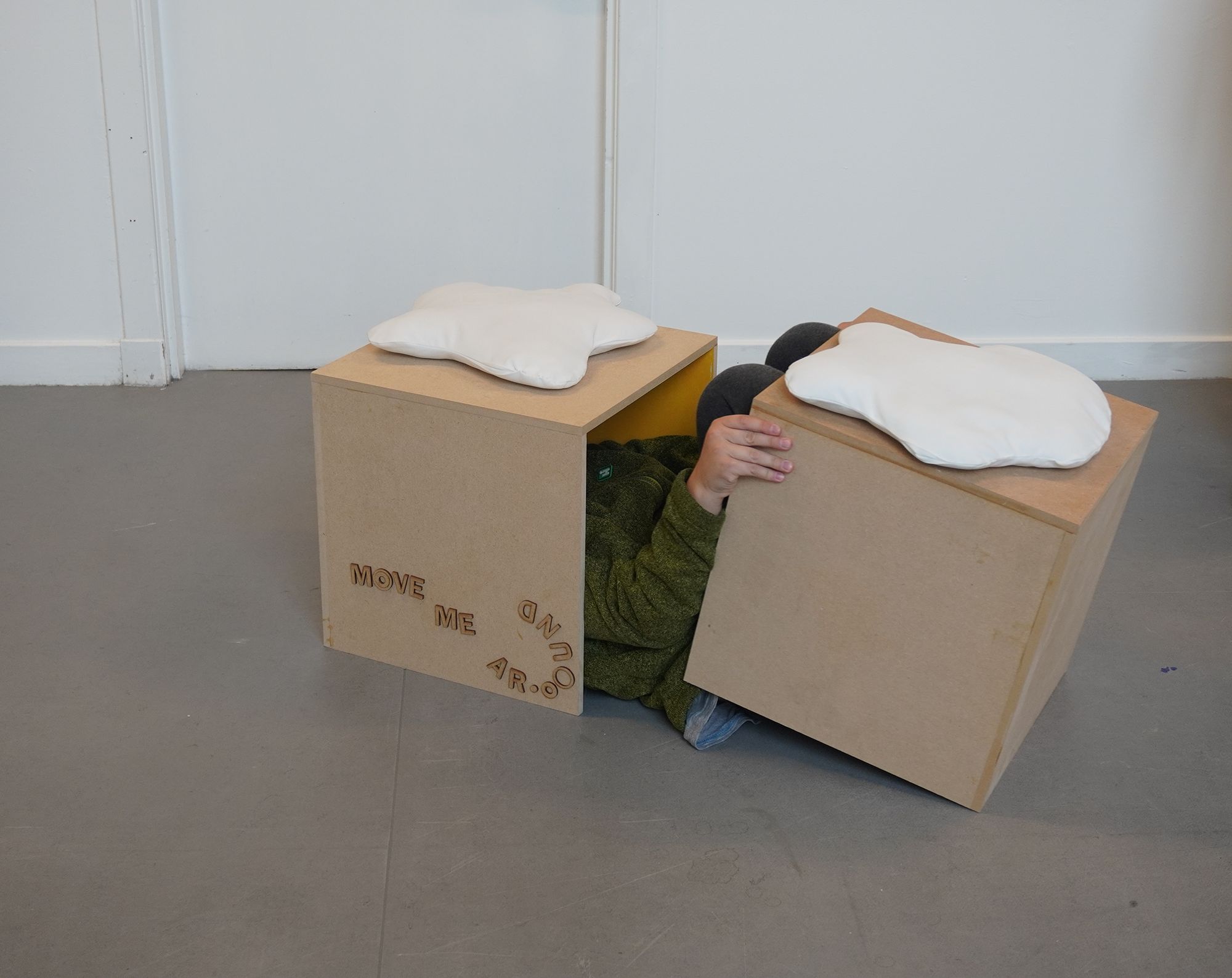 A child playing with the movable stalls, hiding inside of the two stalls. 