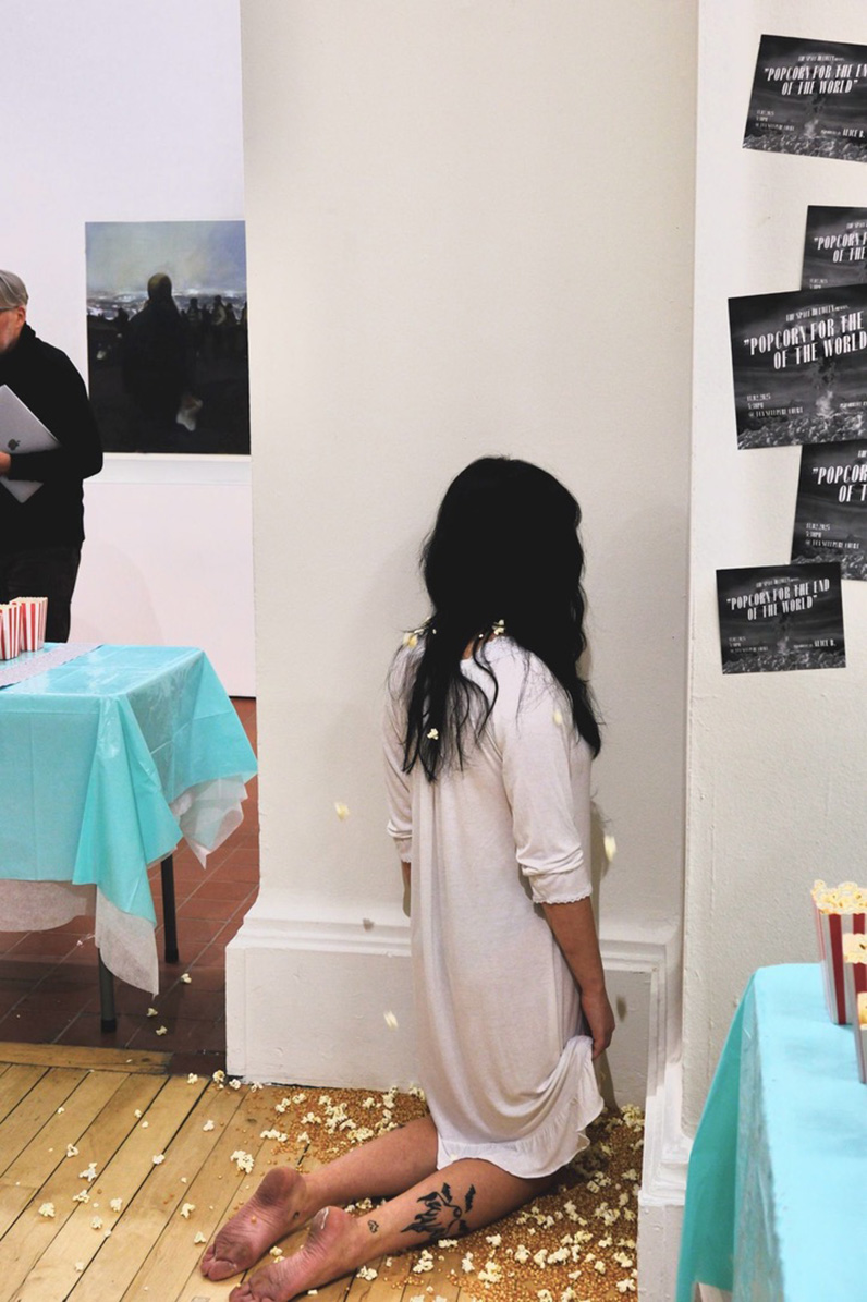 Person in a white dress kneeling in the corner on popcorn kernels