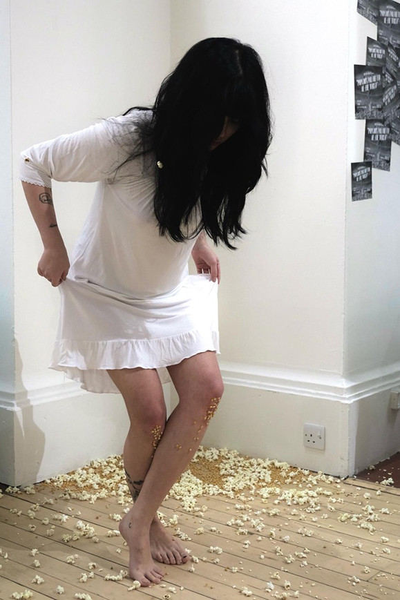 Person in a white dress with popcorn kernels on the knees