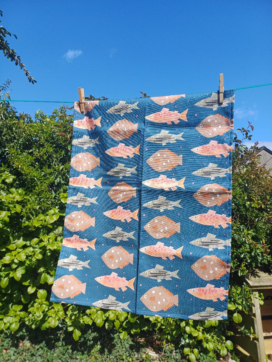 Image of a blue tea towel with a fish pattern.