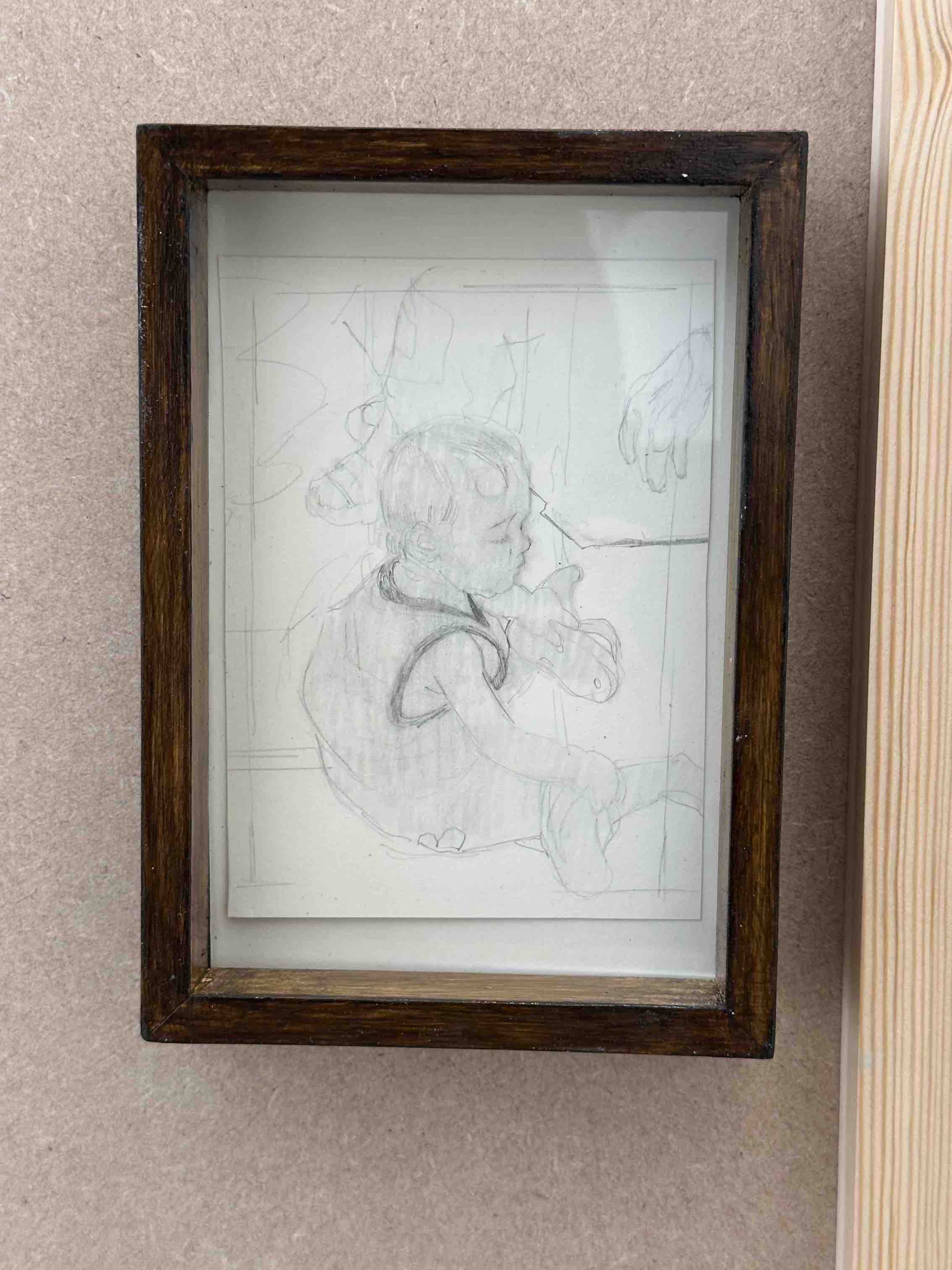 Framed sketch of a little boy sitting on the floor.