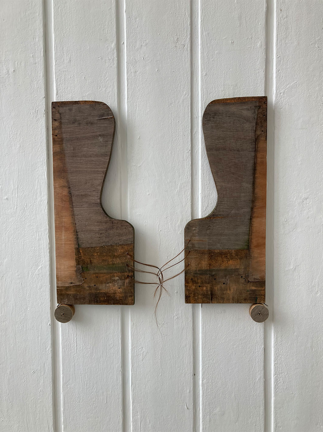 Image of wooden sculpture installed onto wall using sewing needles.