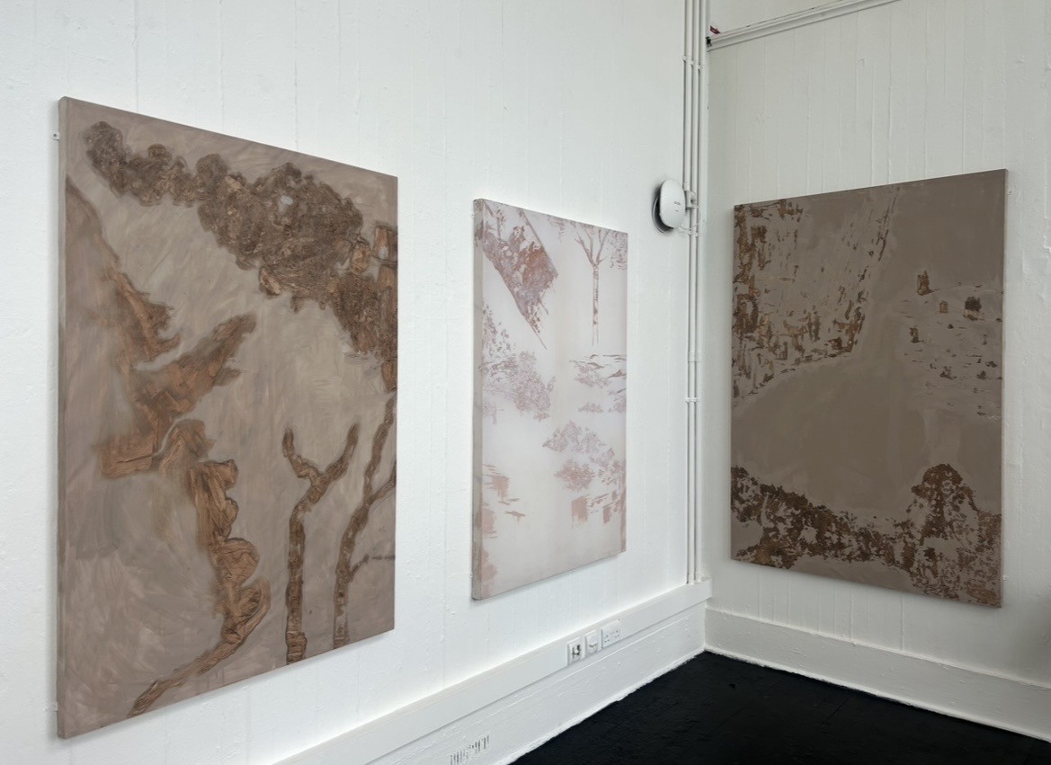 Three paintings displayed on wall.