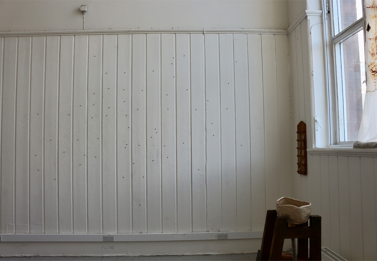 Image of installation made from wooden beads scattered across a wall.