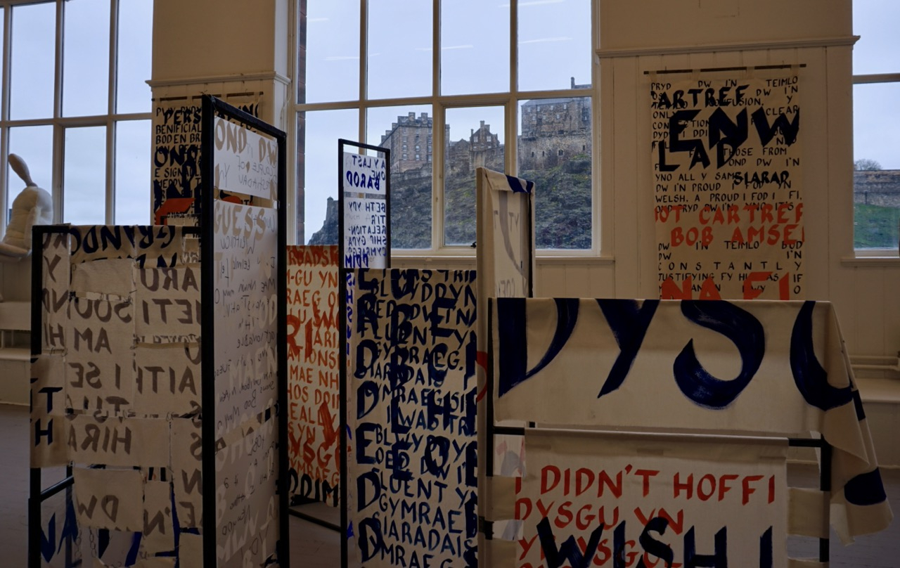 Image of degree show installed, fabric banners with text hanging on metal frames