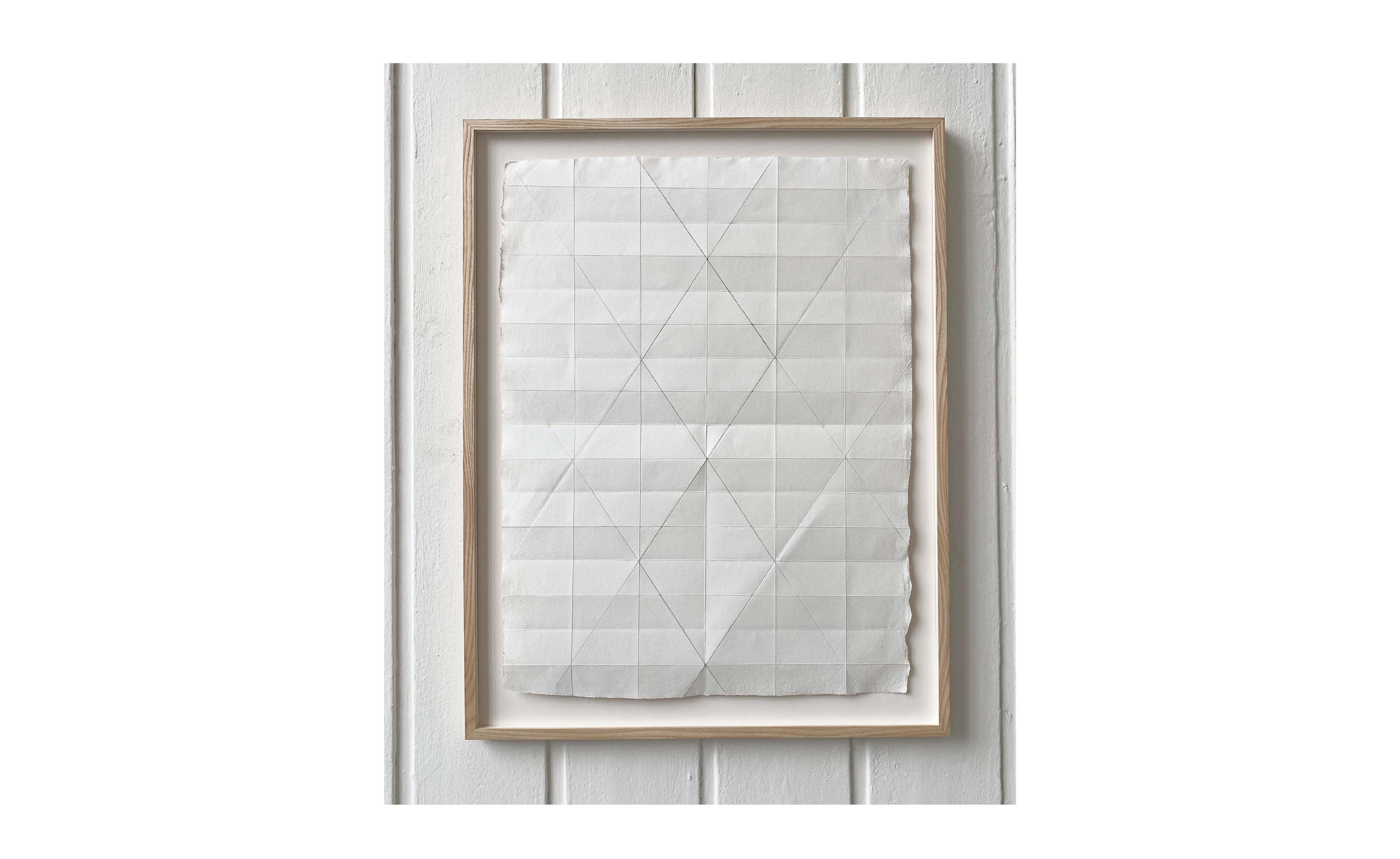 geometric drawing on paper in wooden frame displayed on a wall