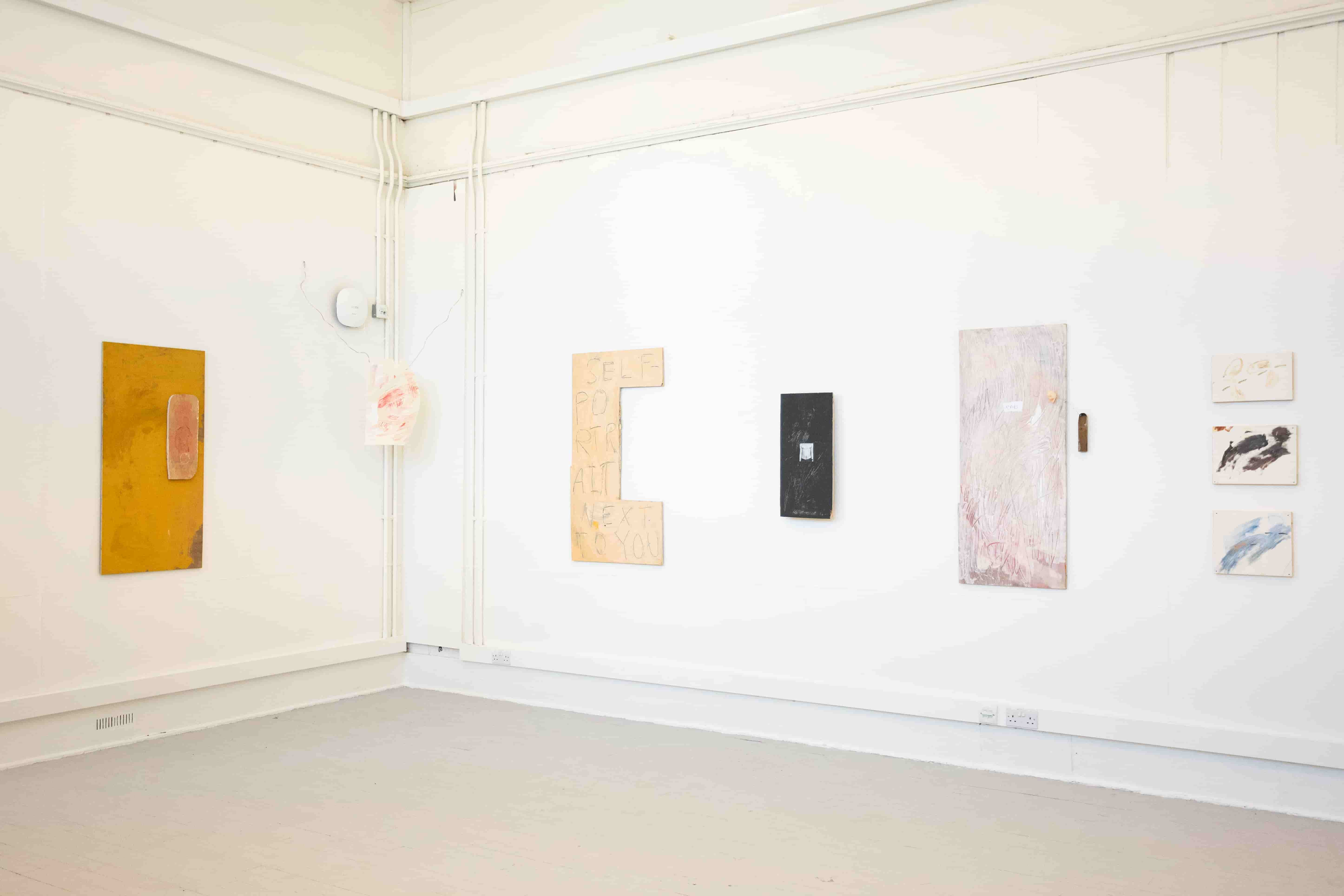 An installation of artworks in a long, cornered space