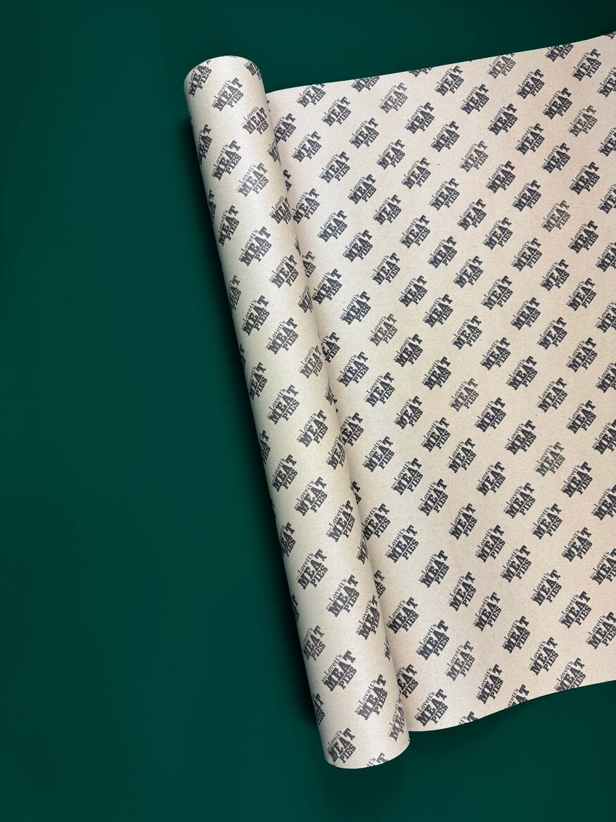 Roll of kraft paper with repeating print pattern that says 'Mrs Lovett's Meat Pies'. Displayed on a dark green background