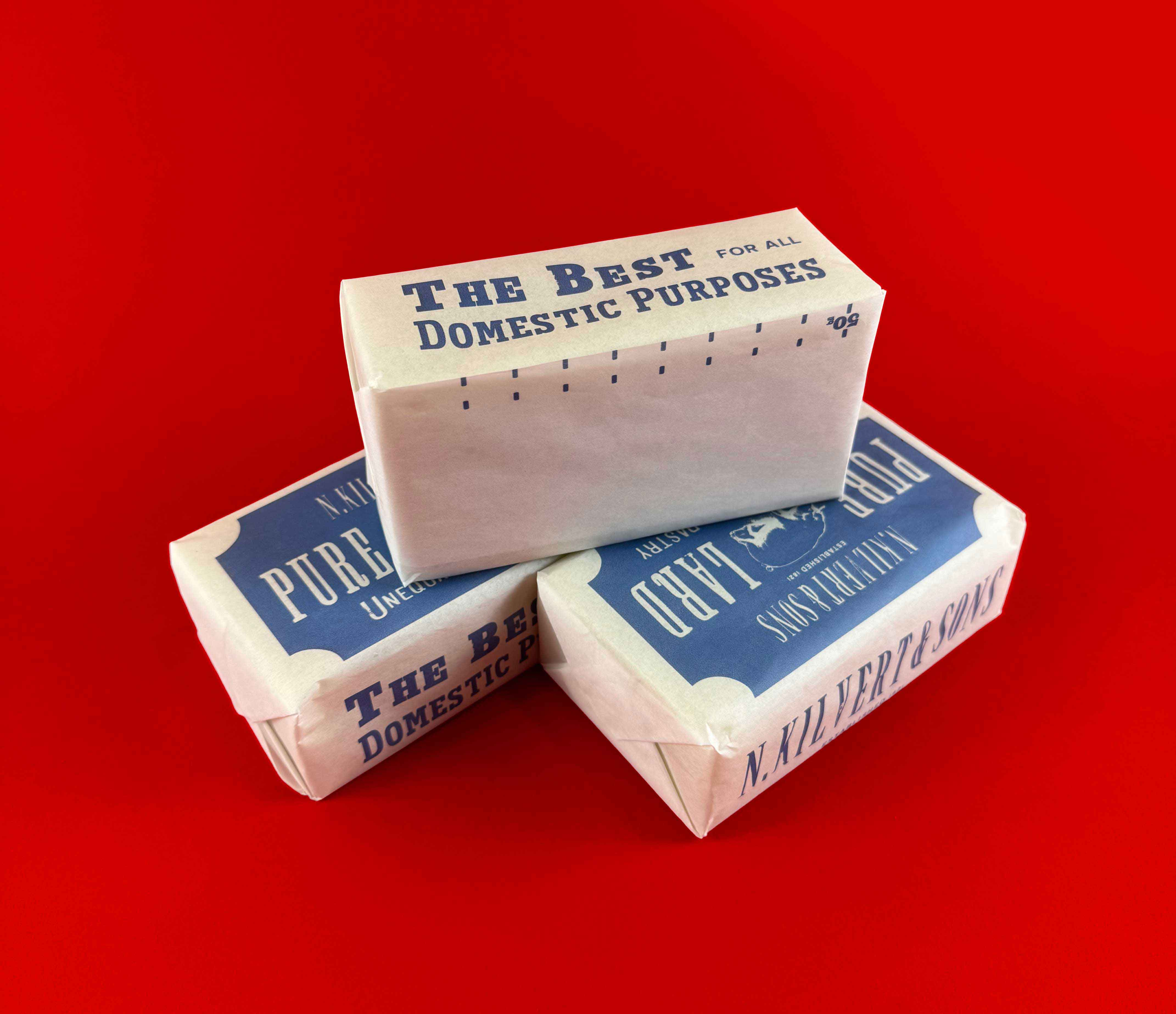 three identical lard products stacked on top of each other displaying slogans and measuring designs. Displayed on a bright red back drop 