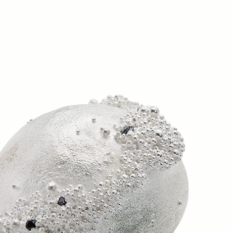 A close up of a silver bead, showing the detail of the ancient technique of granulation.