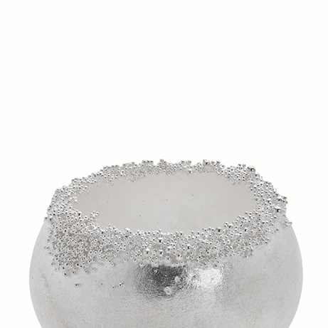 A close up of a silver bead, showing the detail of the ancient technique of granulation.