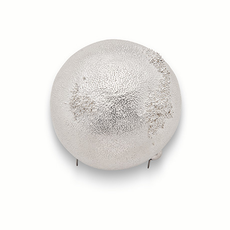 A close up of a silver bead, showing the detail of the ancient technique of granulation.