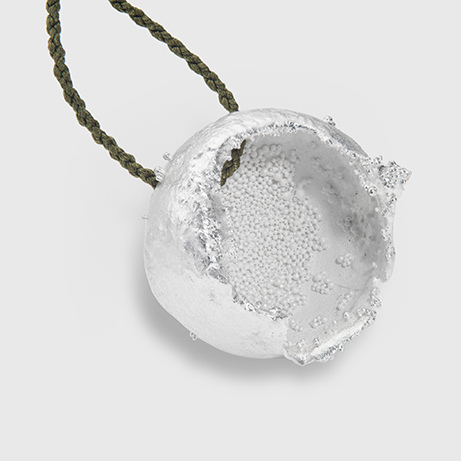 A close up of a metal bead with a bit of black cord looped through the top of it.