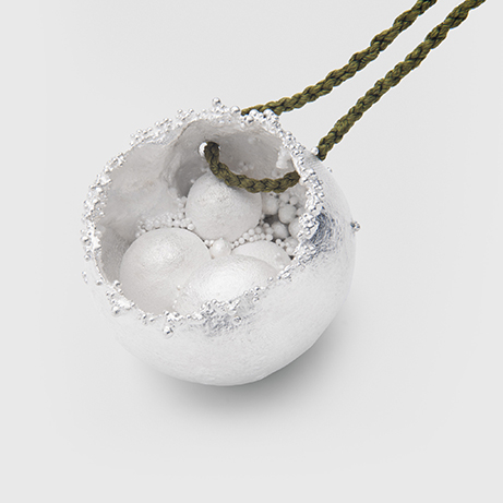 A close up of a metal bead with a bit of black cord looped through the top of it.