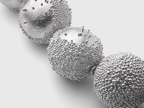 A close up of four metal beads strung together.