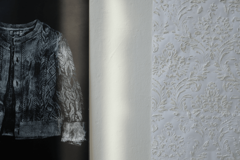 Detail of black and white print of a cardigan and textural wallpaper in background.