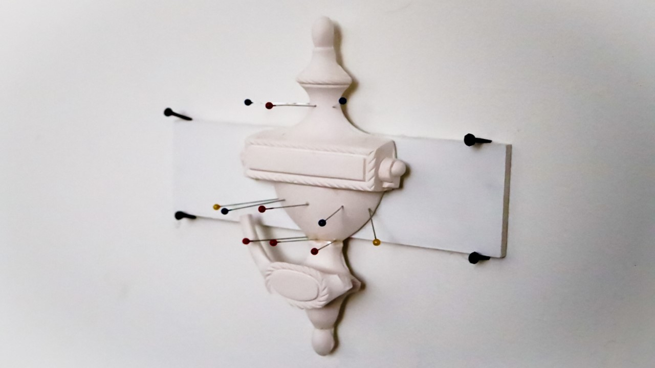 White plaster door knocker with fabric pins inserted into the door knocker