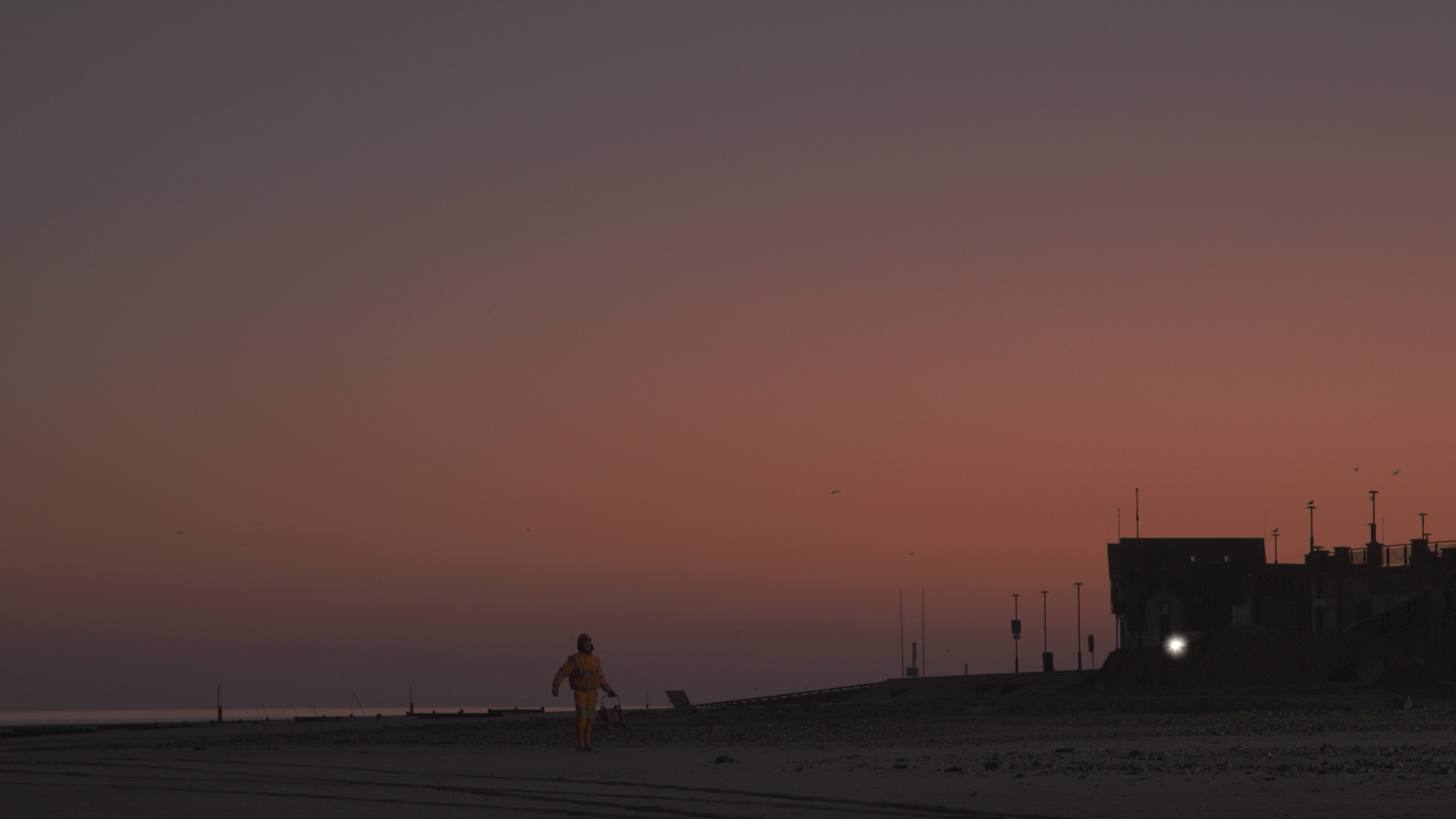 Construction worker walks through sunset