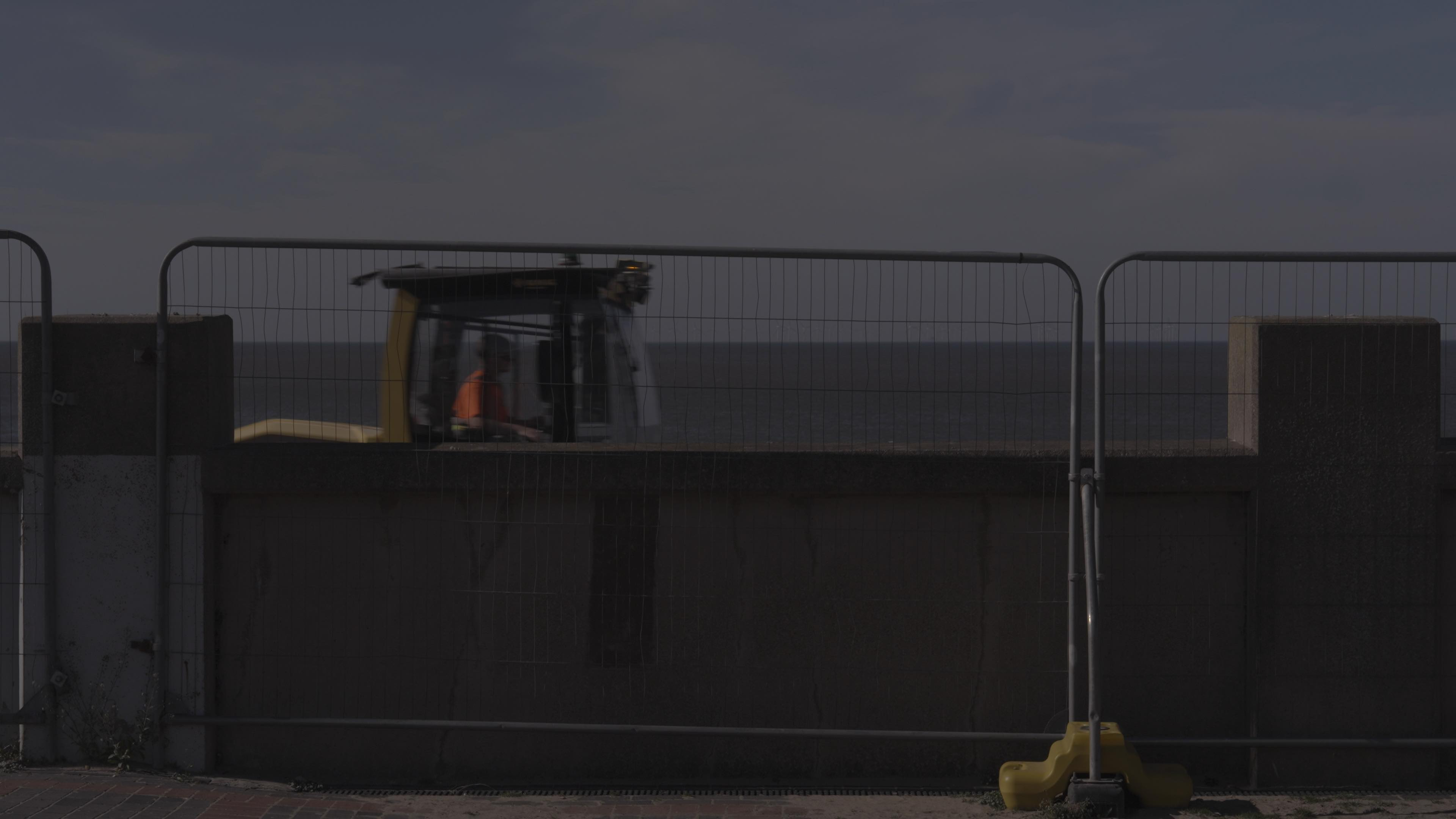 Tractor driving, partially obstructed by wall.