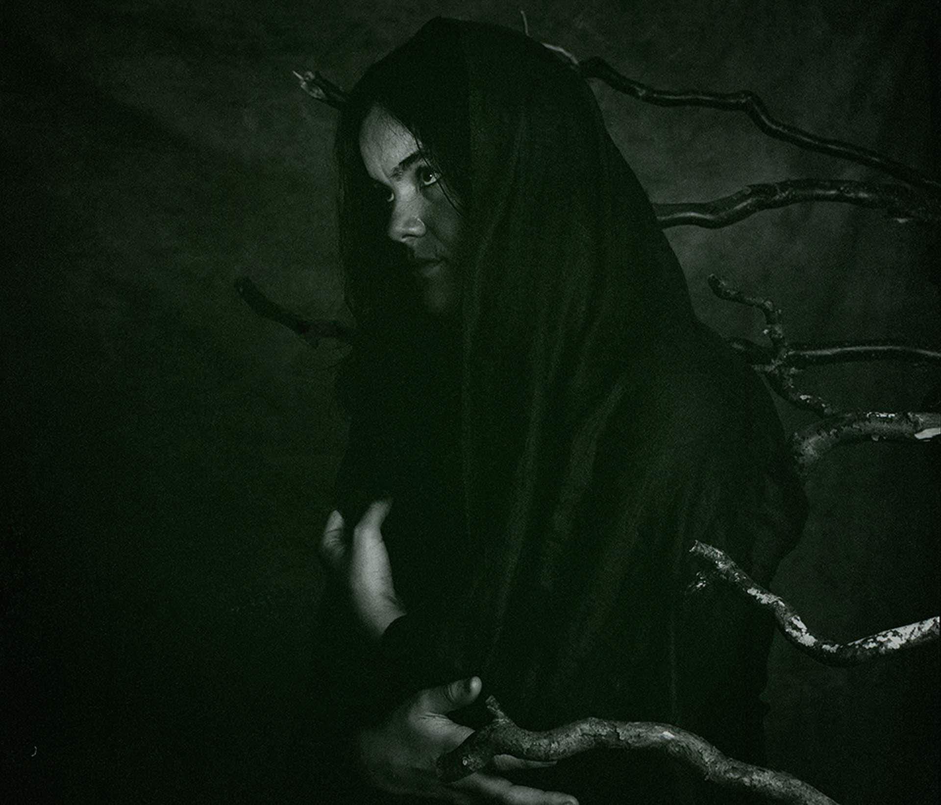 woman stands infront of tree branches 