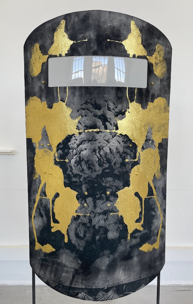 "Blast Shield" screen print, acrylic paint, gold leaf, calico bent birch form, bent acrylic eye slot, strap and handle for utilitarian use 