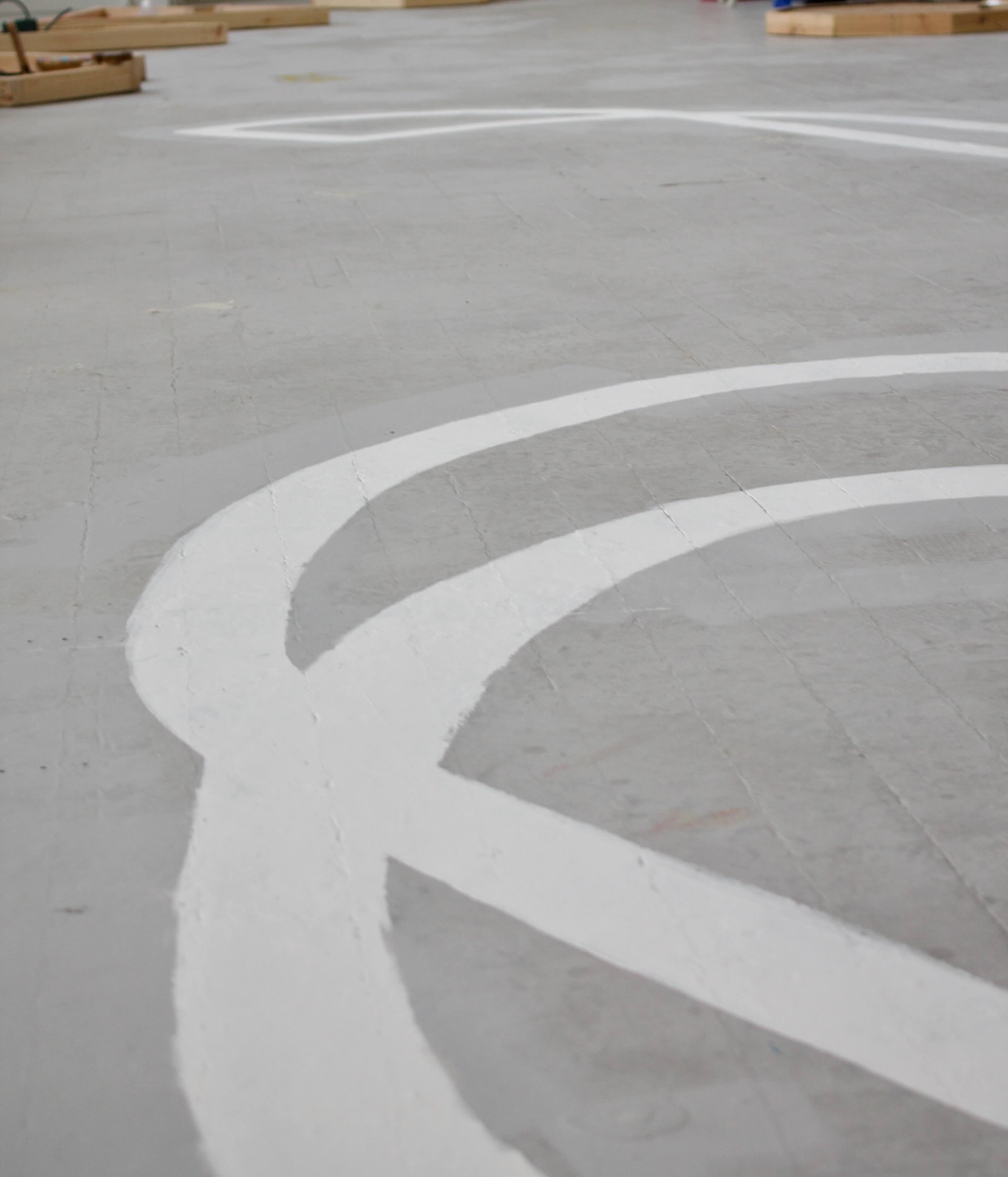 Pictured: details of curved overlapping white outline painted on a grey floor.