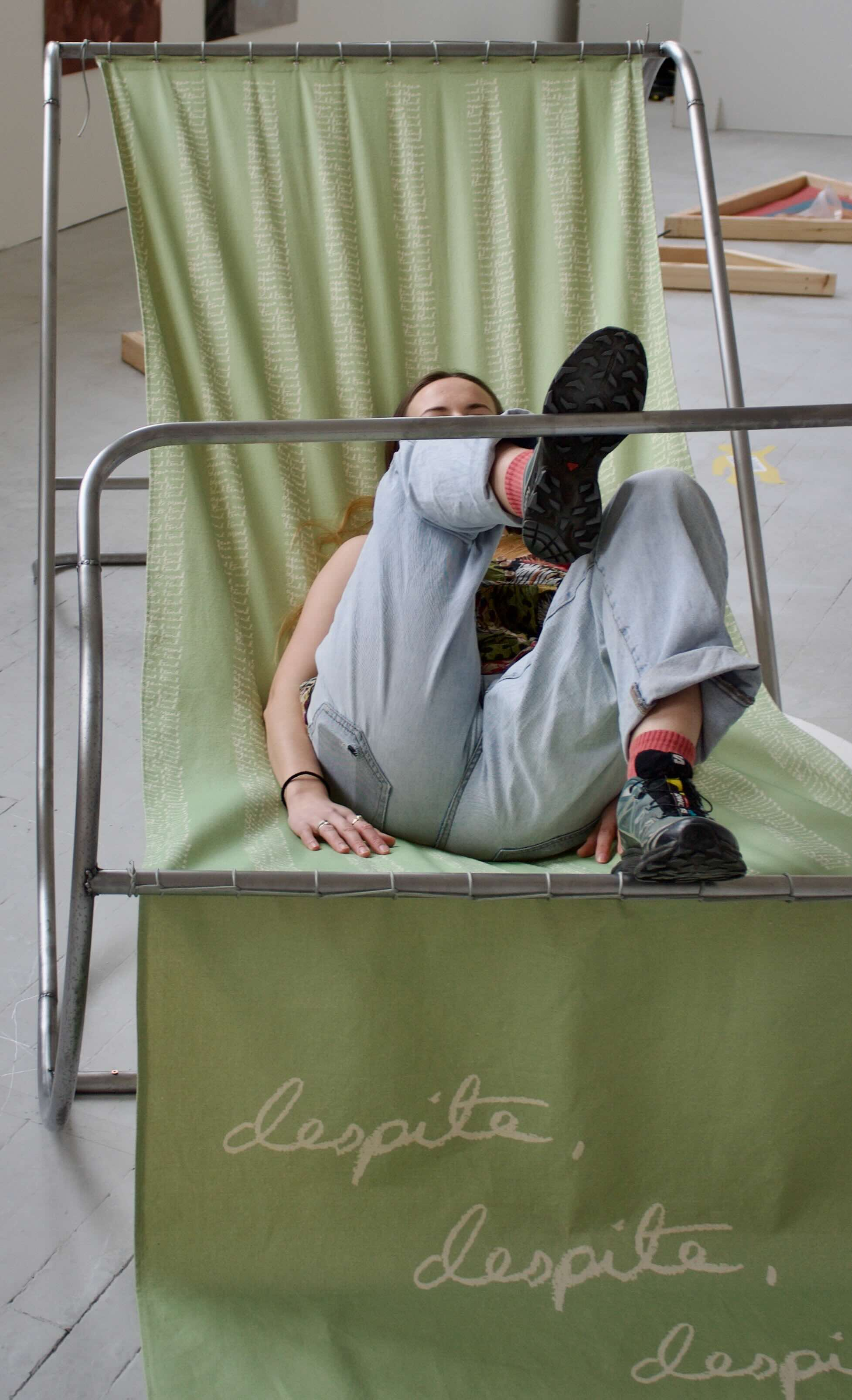 Pictured: a figure sitting on and being held by the fabric of the 'd frame'