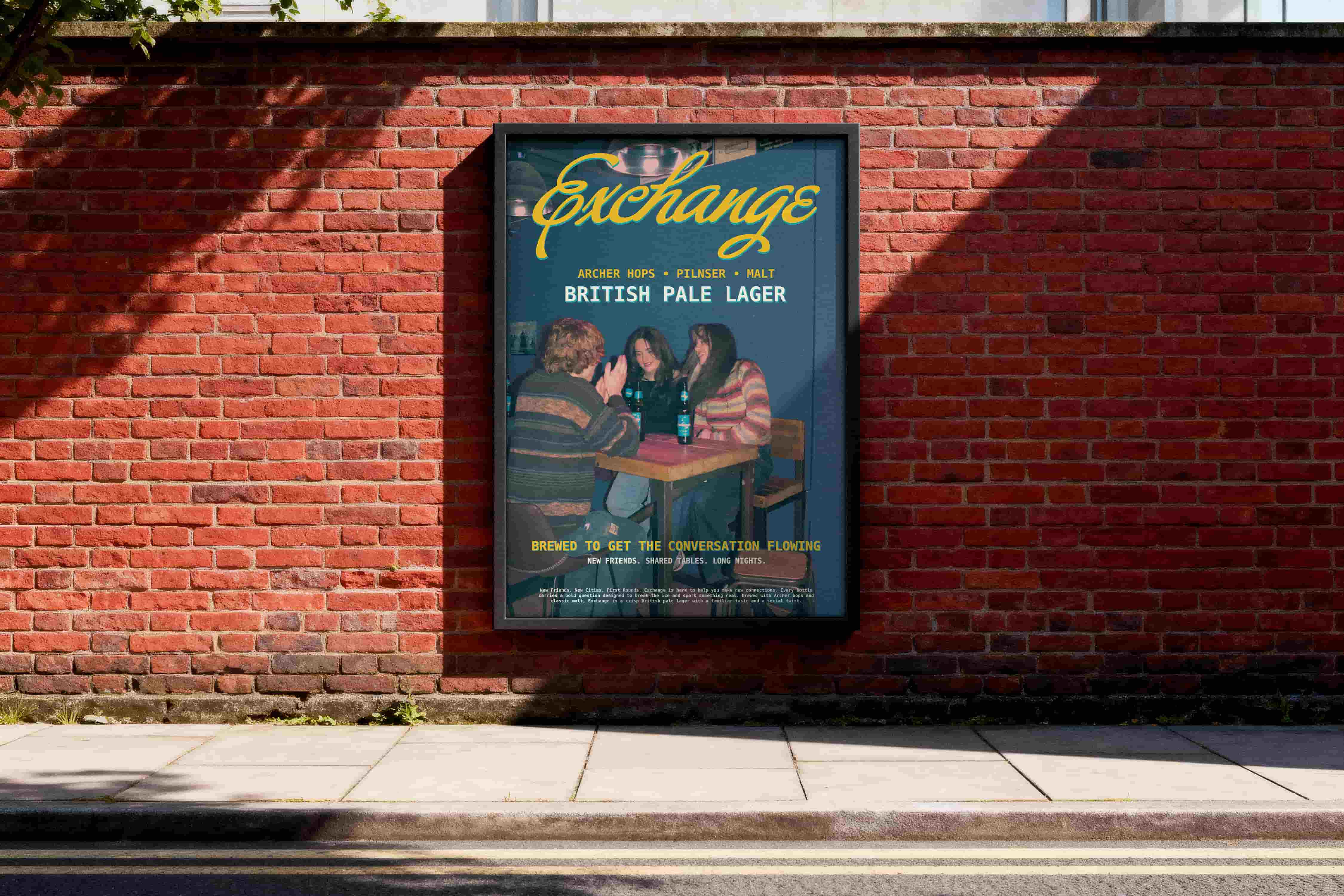     Framed ‘Exchange’ British Pale Lager poster displayed on a red brick wall beside a pavement.