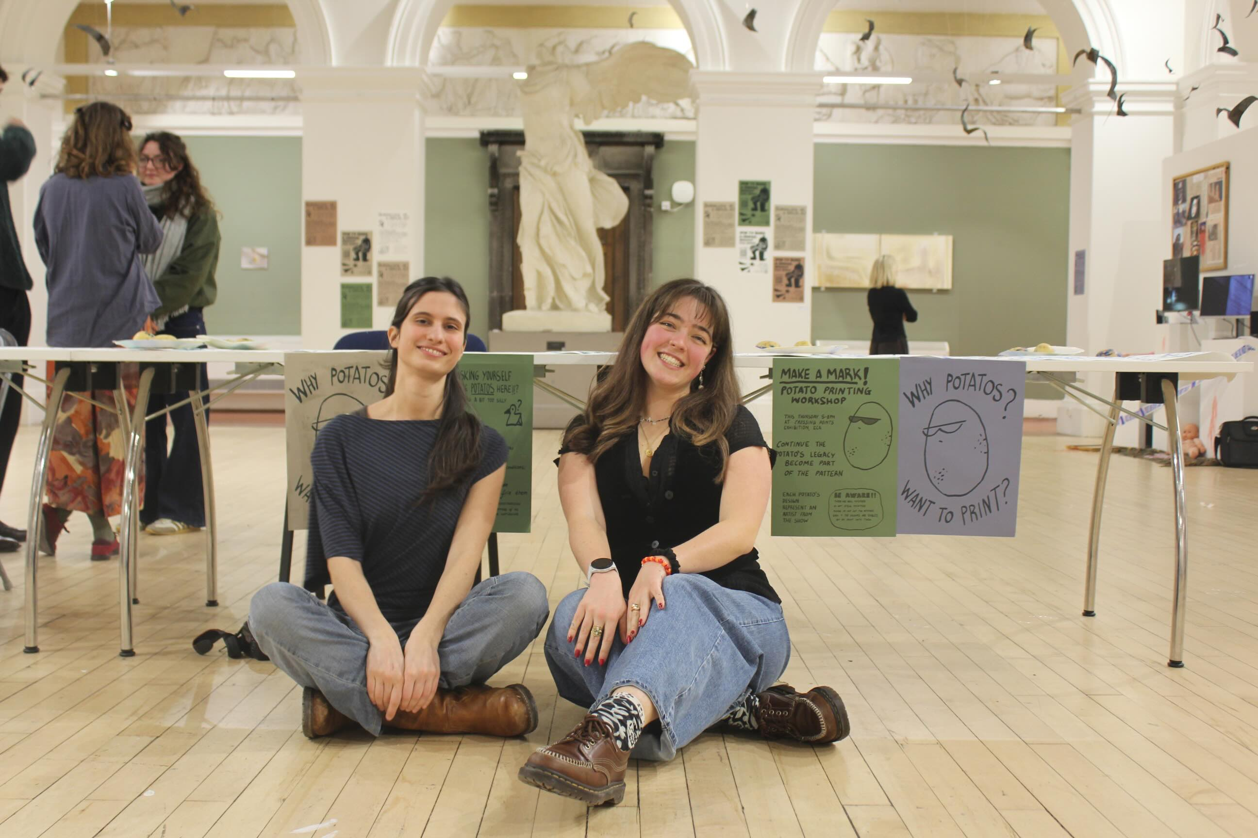 two girls sat in front of a table with potato prints on it