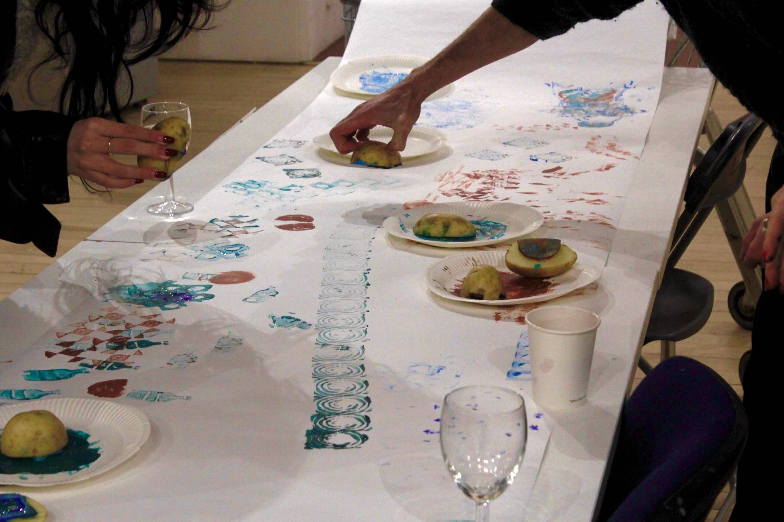 A person leaning over a table printing using a potato