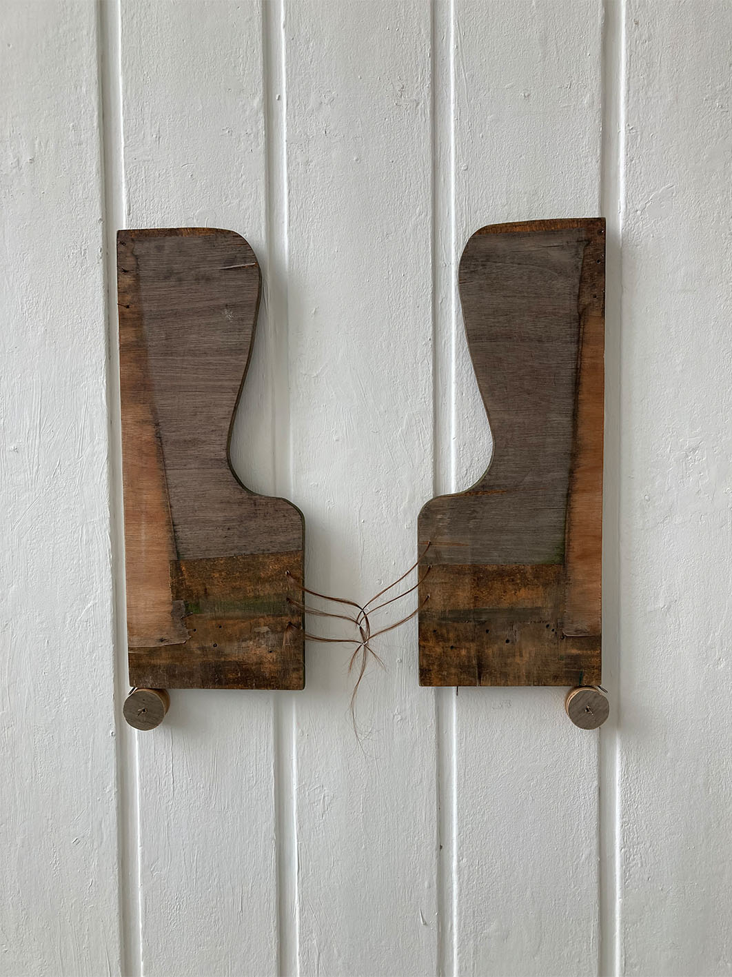 Image of wooden sculpture installed onto wall using sewing needles.