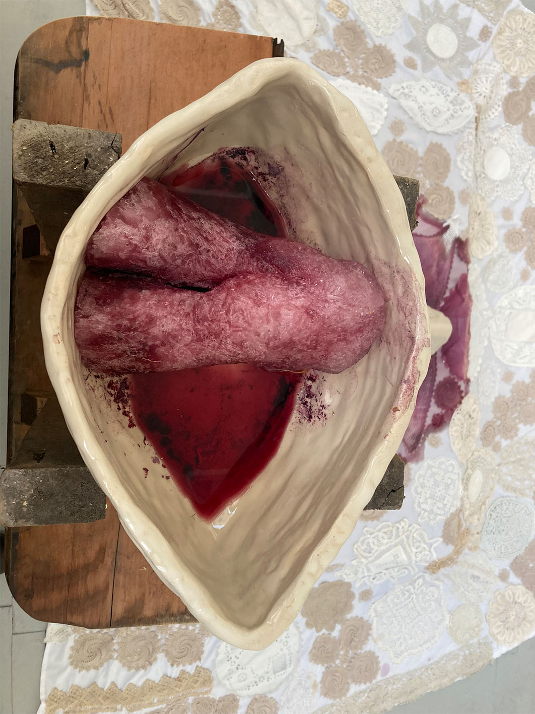 Image of sculture of two hands clasping, made from frozen wine, melting.