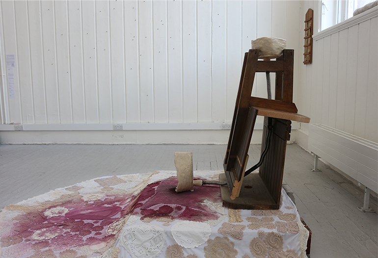 Image of sculpture made from ceramic, wood, metal piping, and textiles.