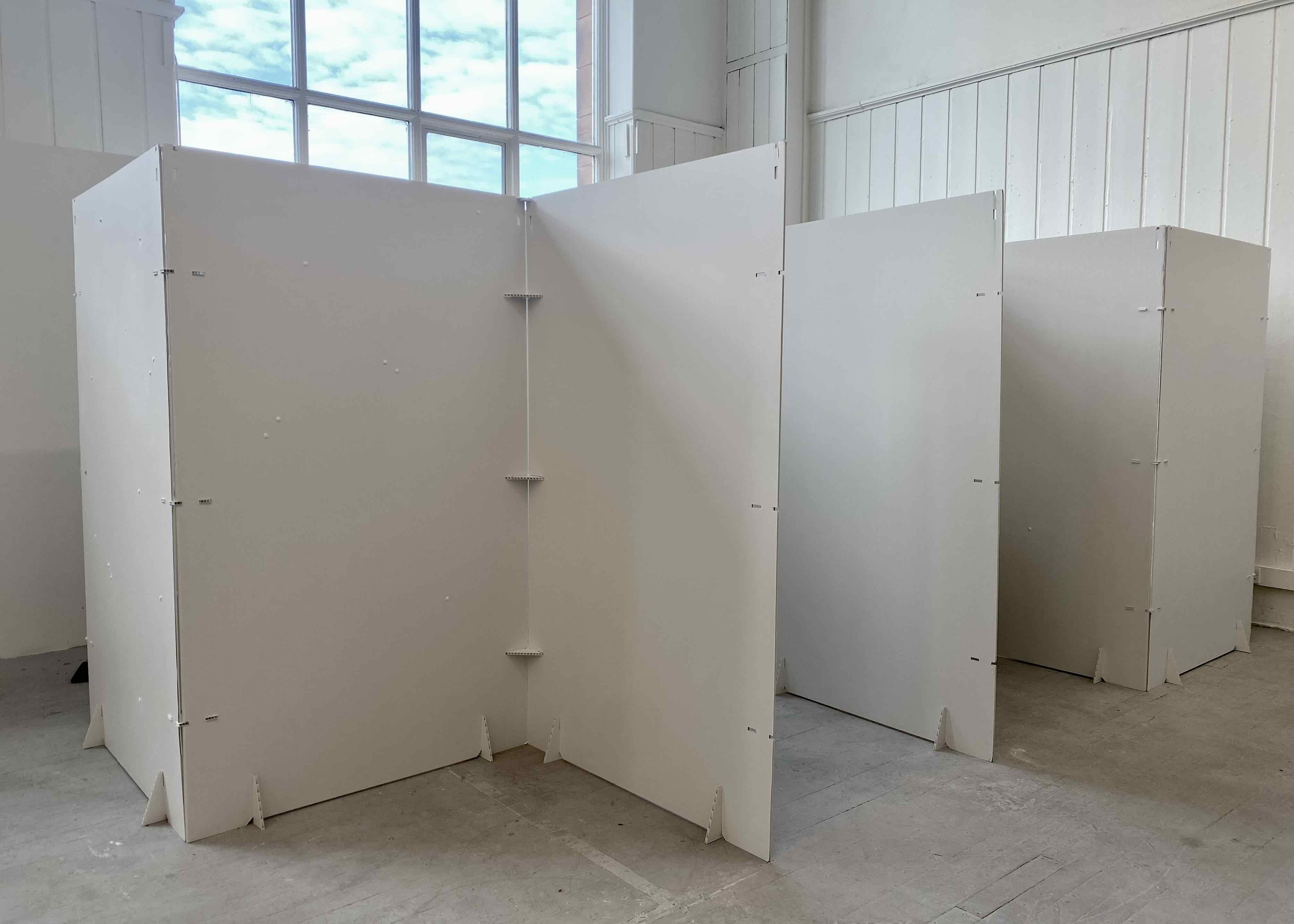 Installation view of sculptural white walls in tunnelled room setup.