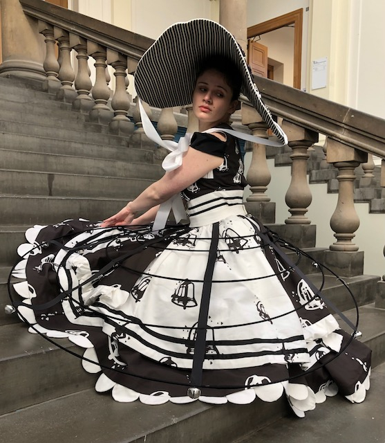 A woman dressed in a black and white costume seated on stairs