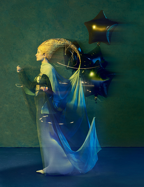 Photo of a sleep fairy with a moon shaped golden hat and helium balloons holding up her veil. 