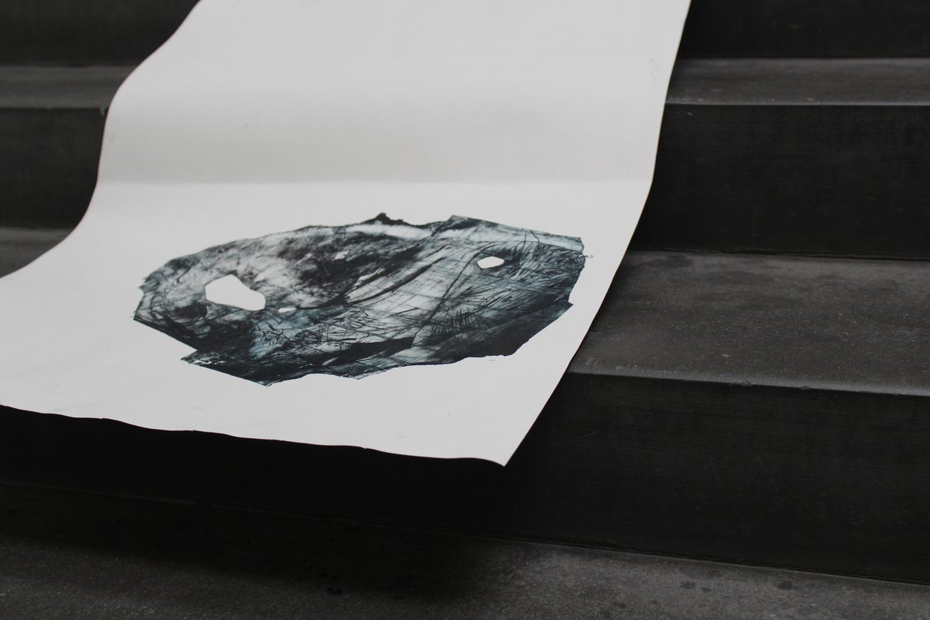 A deep blue amorphous printed form on a white scroll of paper sits on dark grey stairs.