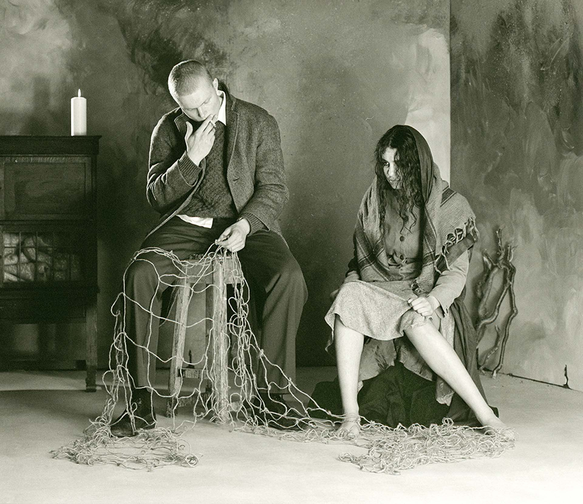 Grey toned image of man[left] and woman [right] sitting together. 